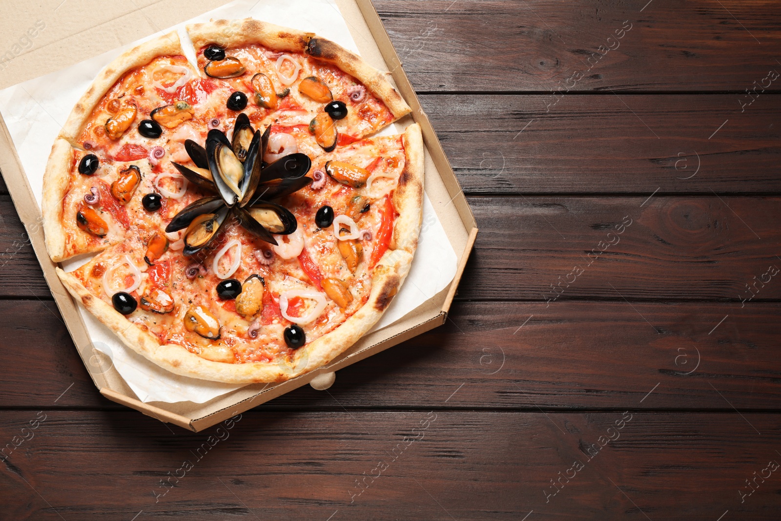Photo of Tasty pizza with seafood on wooden table, top view. Space for text