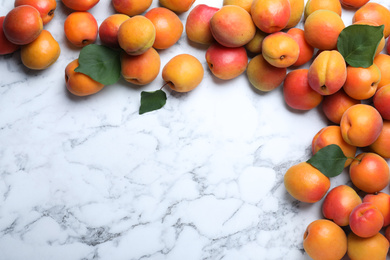 Photo of Many fresh ripe apricots on white marble table, flat lay. Space for text