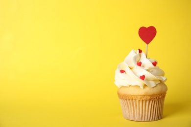 Tasty cupcake on yellow background, space for text. Valentine's Day celebration