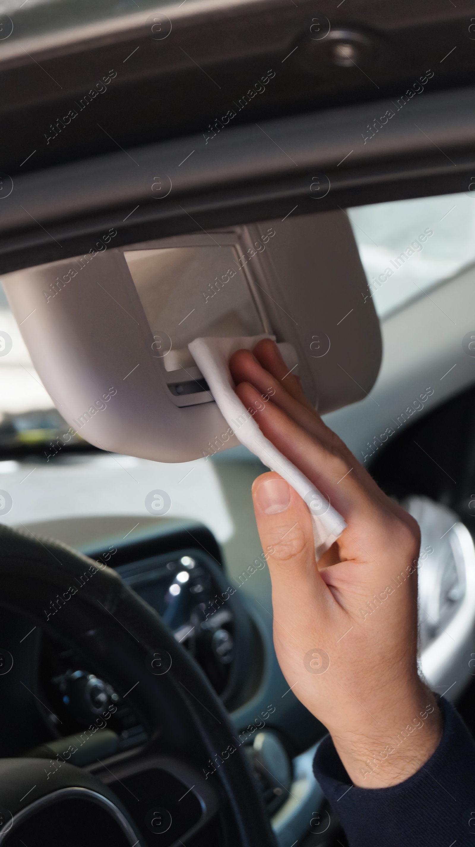 Photo of Man cleaning mirror with wet wipe in car, closeup. Protective measures