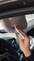 Photo of Man cleaning mirror with wet wipe in car, closeup. Protective measures