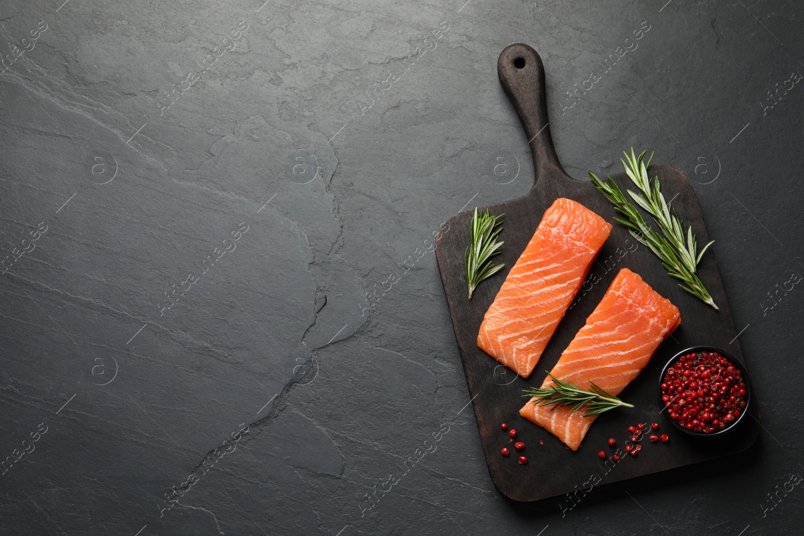 Photo of Fresh raw salmon and spices on black table, top view. Space for text