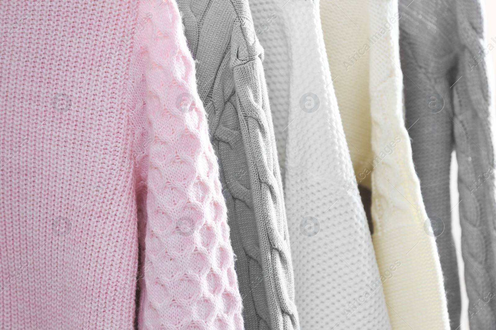Photo of Collection of warm sweaters as background, closeup