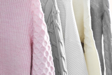 Photo of Collection of warm sweaters as background, closeup