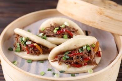 Photo of Delicious gua bao (pork belly buns) in bamboo steamer on table, closeup