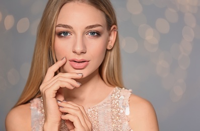Photo of Beautiful young woman with shiny manicure on blurred background, space for text. Nail polish trends