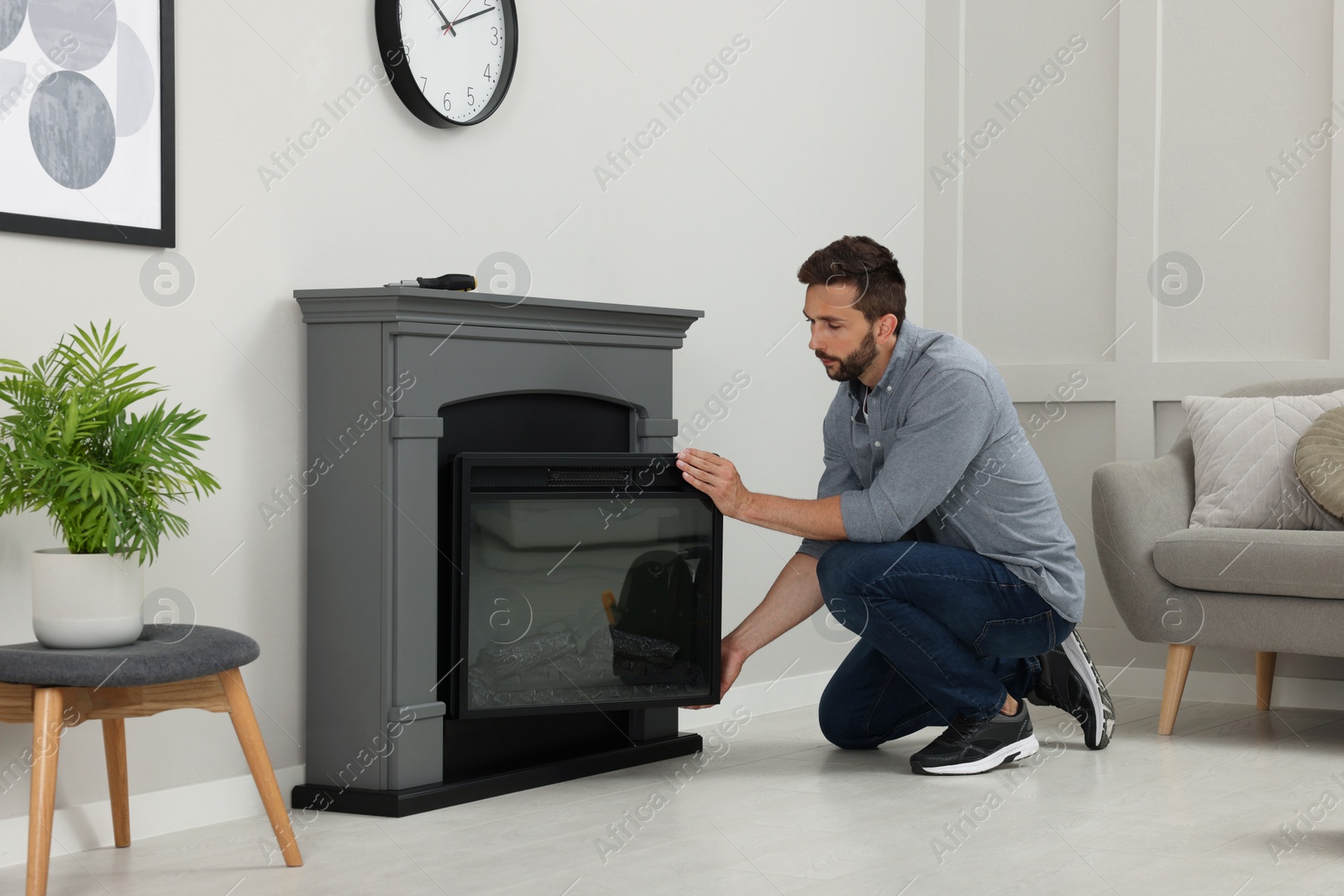 Photo of Man installing electric fireplace near wall in room