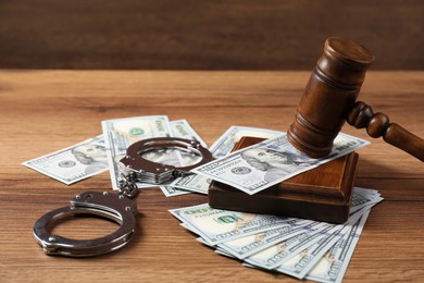 Photo of Judge's gavel, money and handcuffs on wooden table