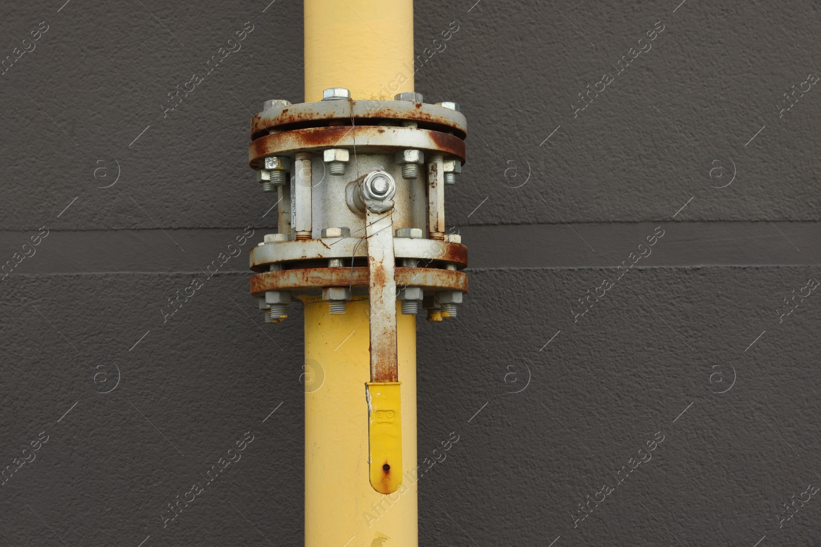 Photo of Yellow gas pipe with valve near brick wall outdoors