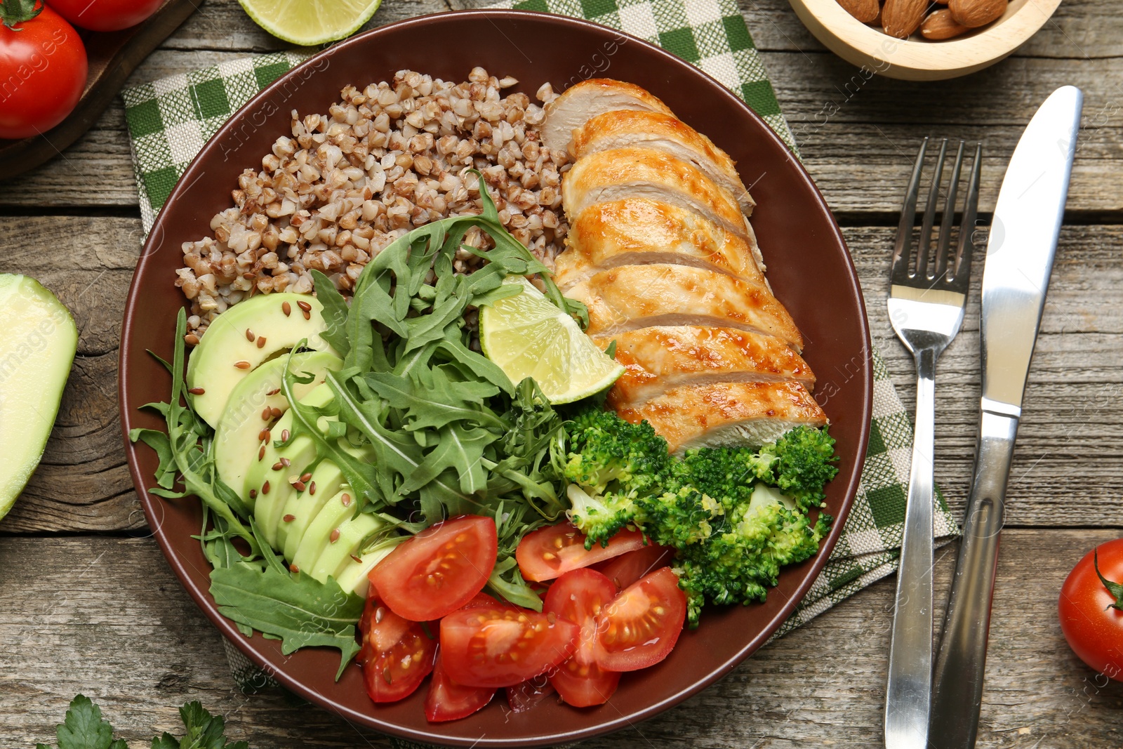 Photo of Healthy meal. Tasty products in bowl, ingredients and cutlery on wooden table, flat lay