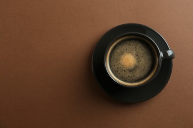 Photo of Cup of tasty coffee on brown background, top view. Space for text