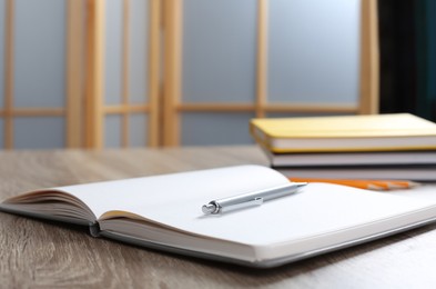 Photo of Notebook with pen on wooden table indoors, space for text