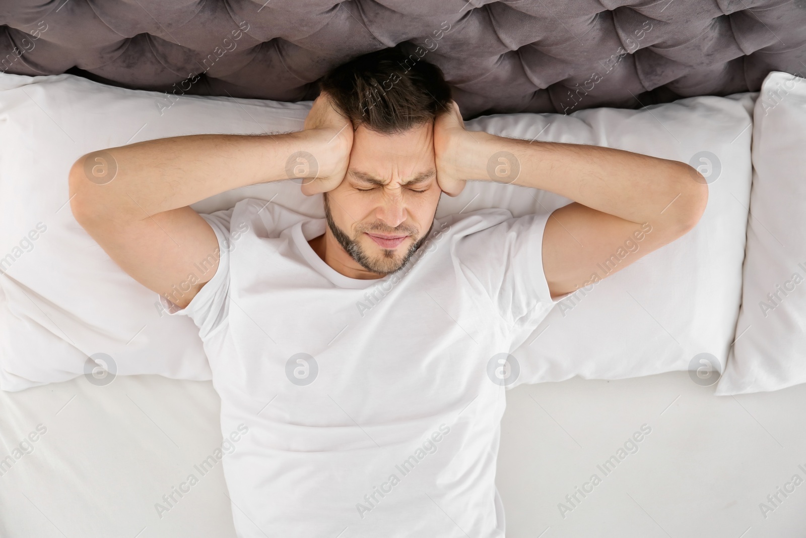 Photo of Man suffering from head ache in bedroom
