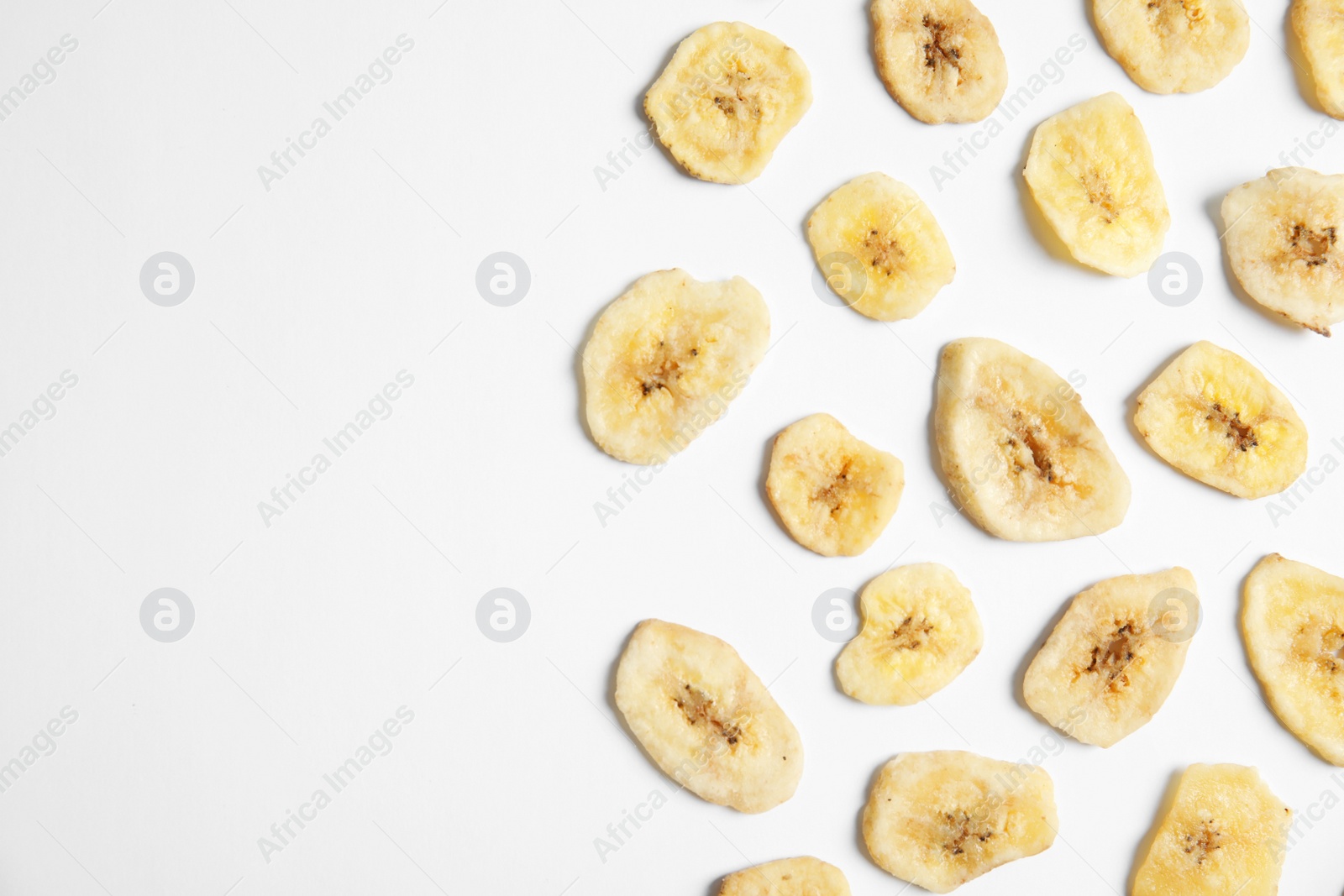 Photo of Flat lay composition with banana slices on  white background, space for text. Dried fruit as healthy snack