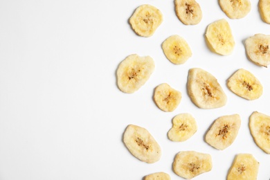 Photo of Flat lay composition with banana slices on  white background, space for text. Dried fruit as healthy snack