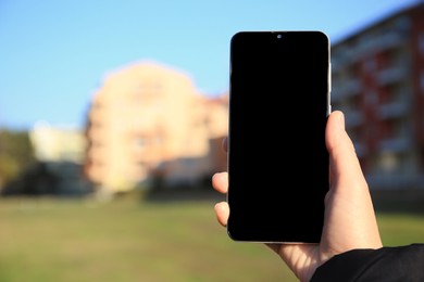 Photo of Woman holding mobile phone outdoors on sunny day, closeup. Space for text