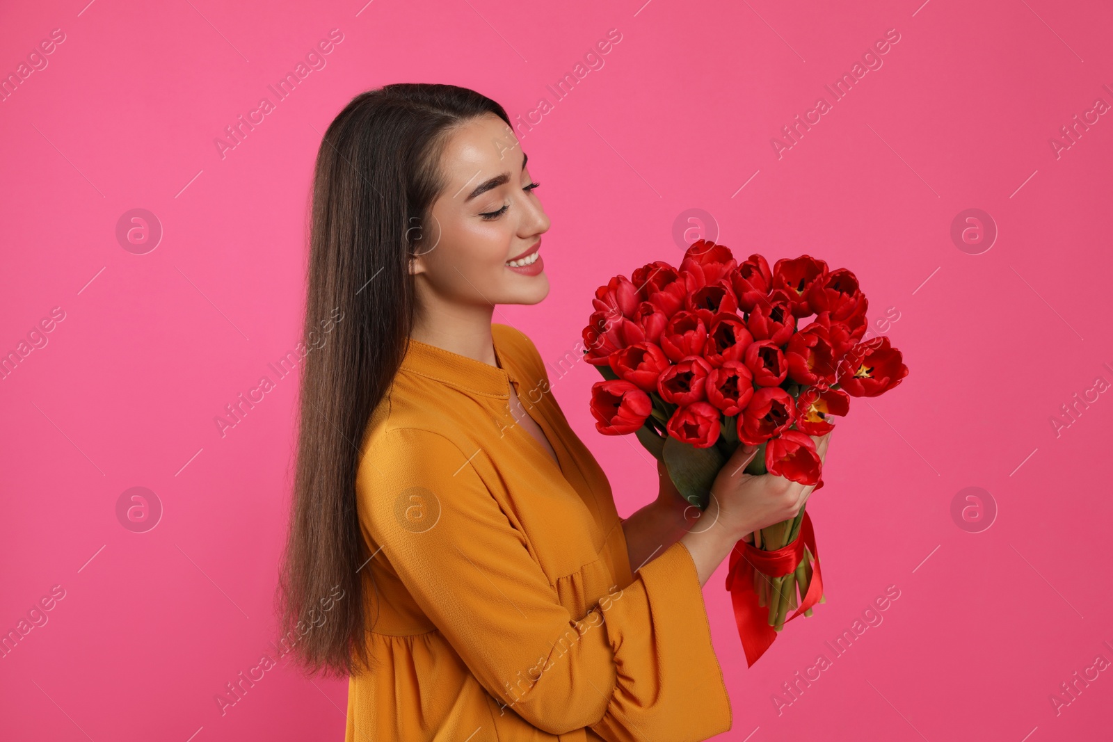 Photo of Happy woman with red tulip bouquet on pink background. 8th of March celebration