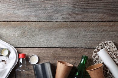 Photo of Recycling symbol and garbage on wooden table, flat lay