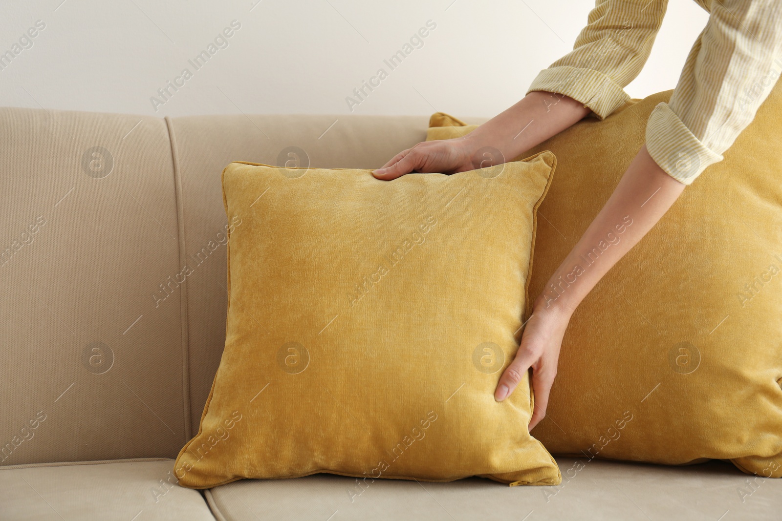 Image of Woman putting yellow pillow onto sofa, closeup view. Interior design