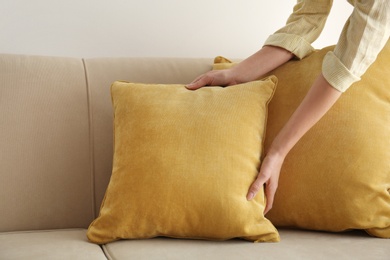Image of Woman putting yellow pillow onto sofa, closeup view. Interior design