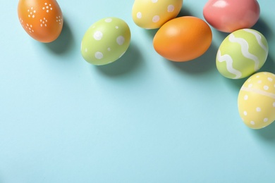 Flat lay composition of painted Easter eggs on color background, space for text