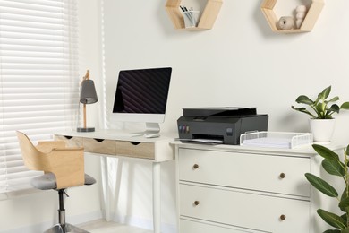 Photo of Stylish workplace with modern computer, printer and lamp