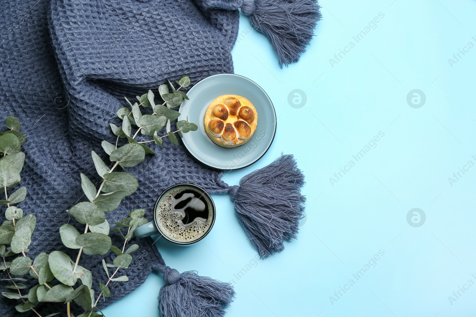 Photo of Flat lay composition with hot drink and warm plaid on light blue background, space for text