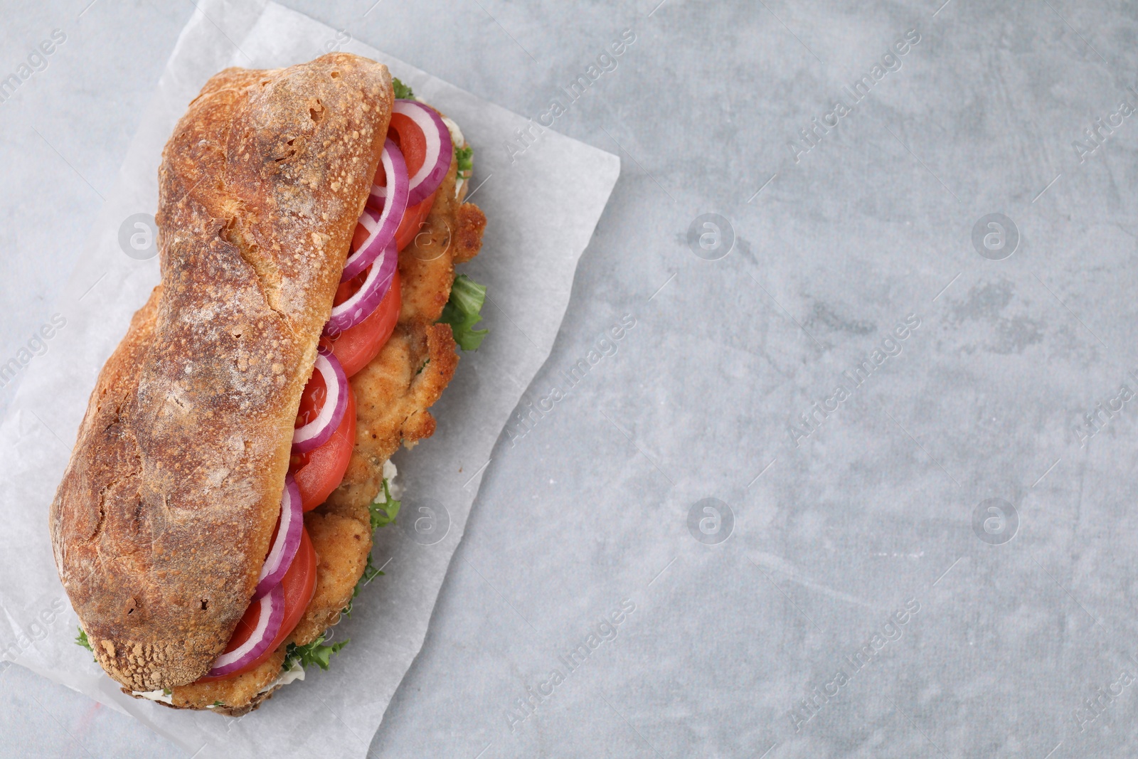 Photo of Delicious sandwich with schnitzel on grey table, top view. Space for text