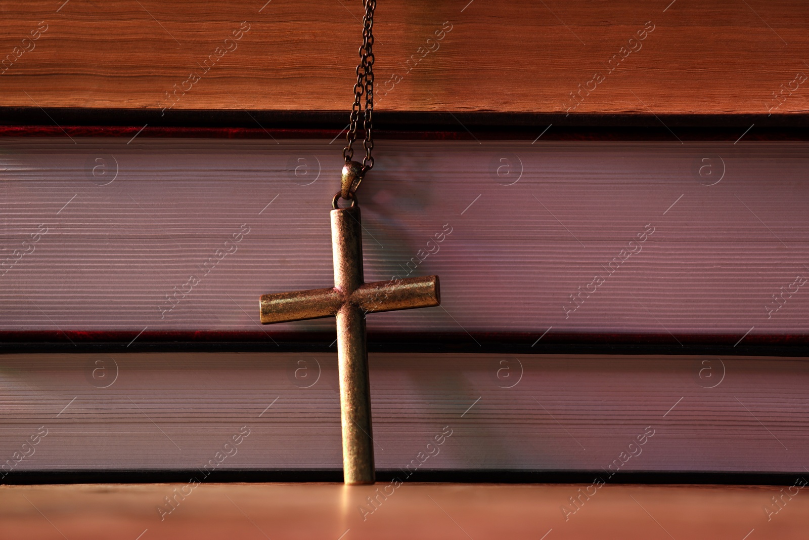 Photo of Cross and stack of books on table, closeup. Religion of Christianity