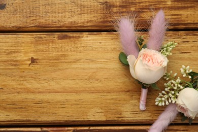 Photo of Small stylish boutonnieres on wooden table, flat lay. Space for text