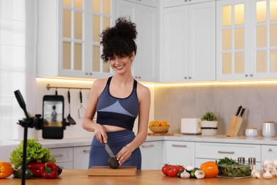 Photo of Smiling food blogger cooking while recording video in kitchen