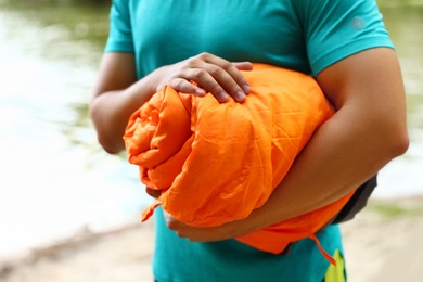 Man holding rolled sleeping bag outdoors, closeup