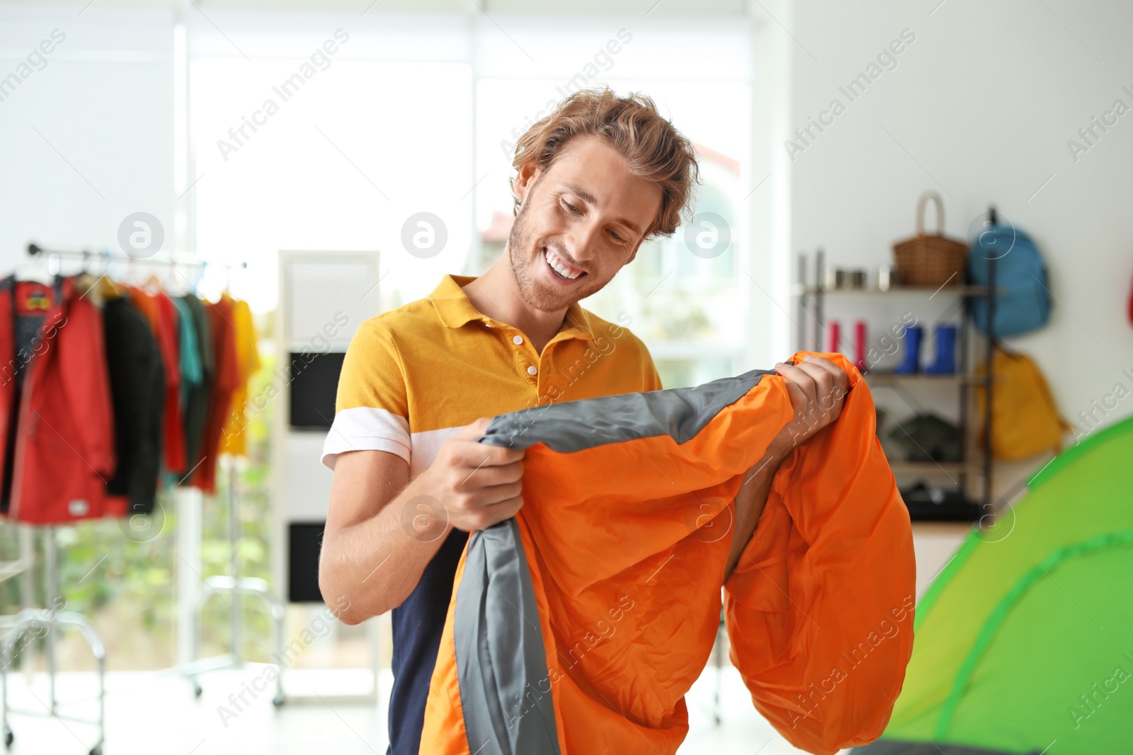 Photo of Young man choosing sleeping bag in store