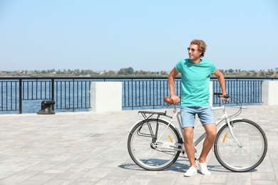 Handsome young man with bicycle outdoors on sunny day