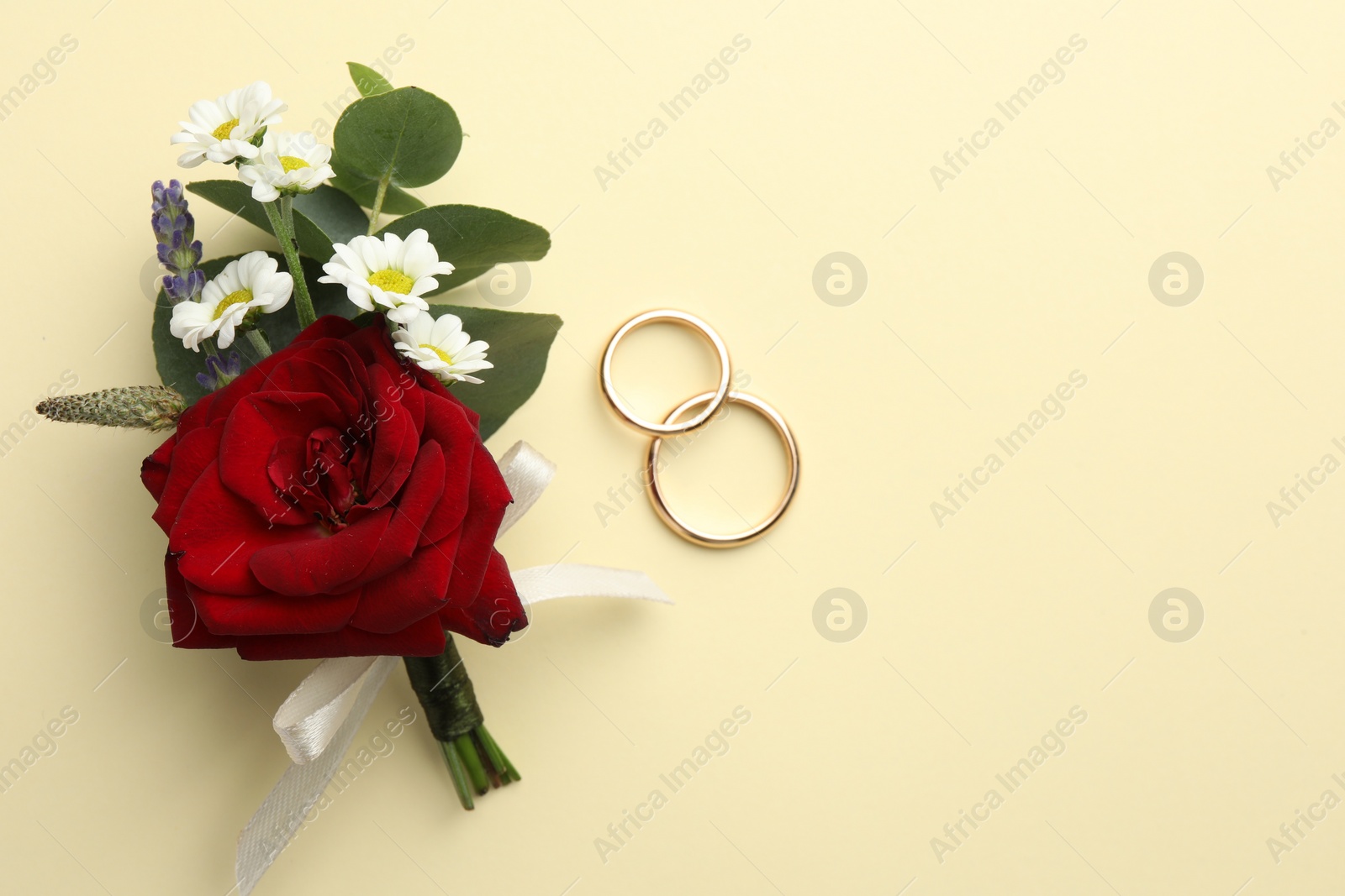 Photo of Small stylish boutonniere and rings on beige background, flat lay. Space for text