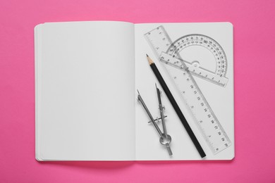 Photo of Rulers, compass, pencil and notebook on pink background, flat lay