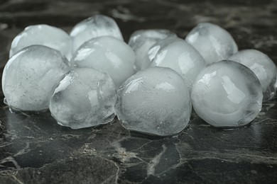 Photo of Many frozen ice balls on black marble table, closeup