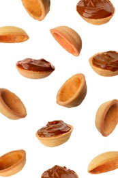 Image of Many empty and filled with caramelized condensed milk nut shell shaped cookie parts falling on white background