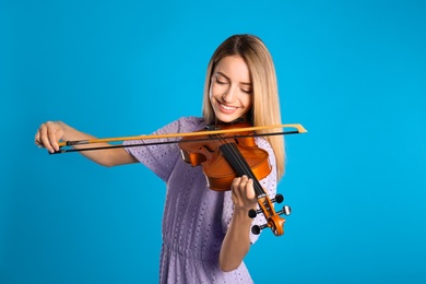 Photo of Beautiful woman playing violin on blue background