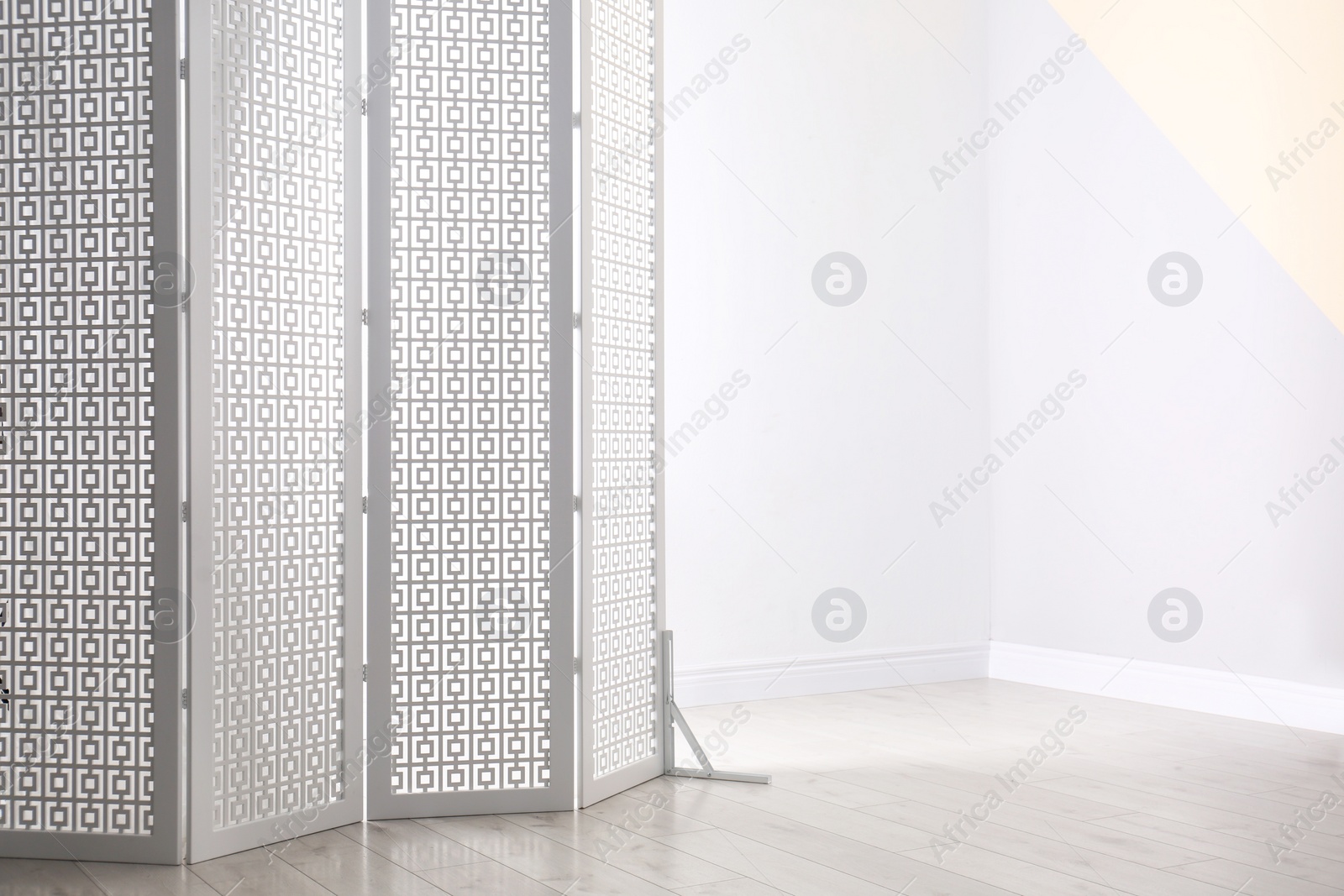 Photo of White decorative folding screen near color wall. Space for text