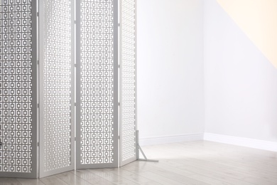 Photo of White decorative folding screen near color wall. Space for text