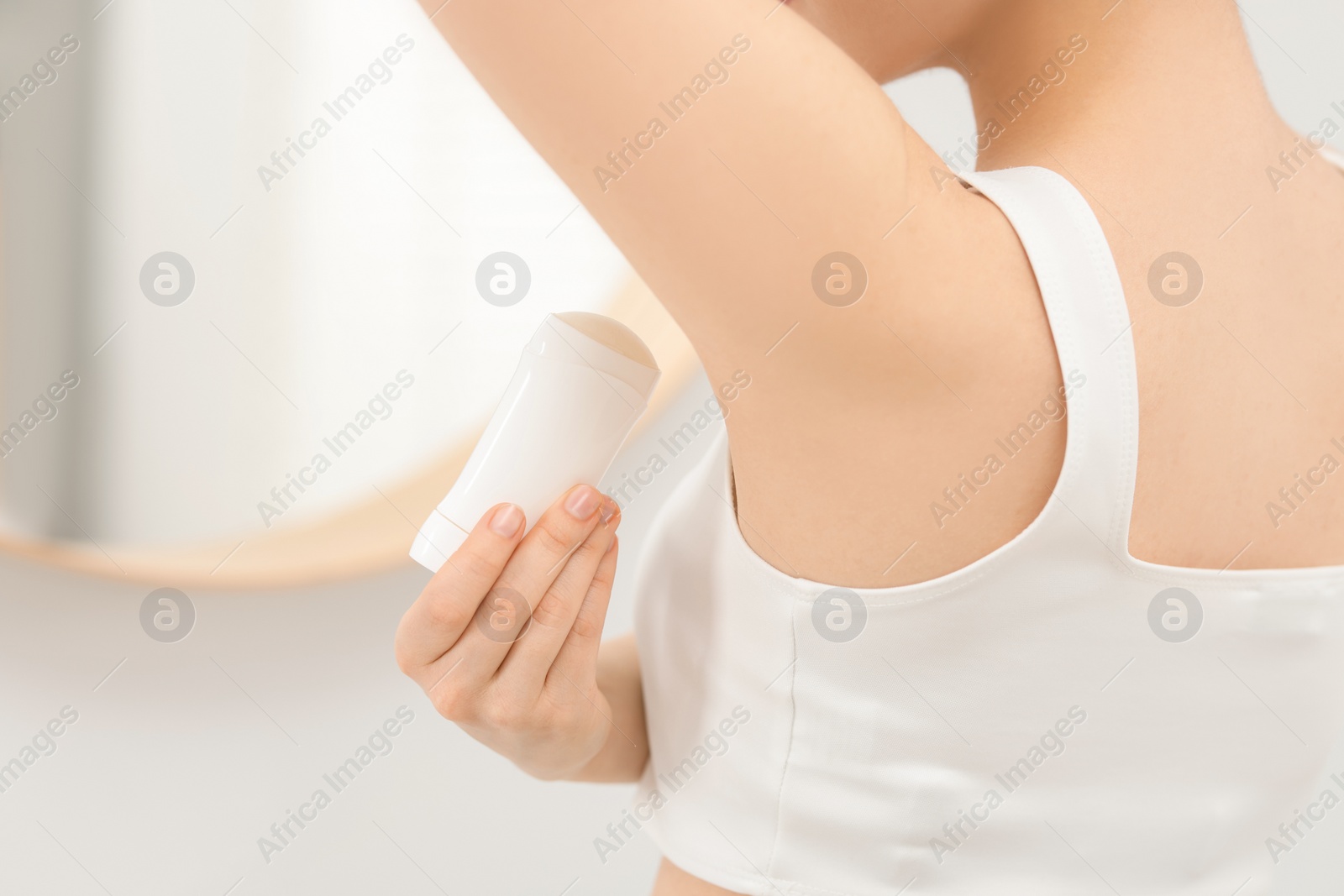 Photo of Beautiful woman applying deodorant in bathroom, closeup