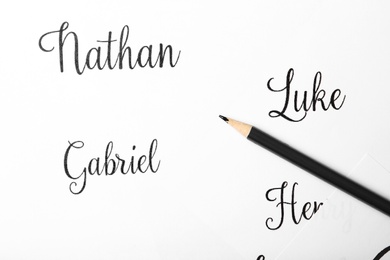 Photo of Ordinary pencil and different baby names written on paper, top view