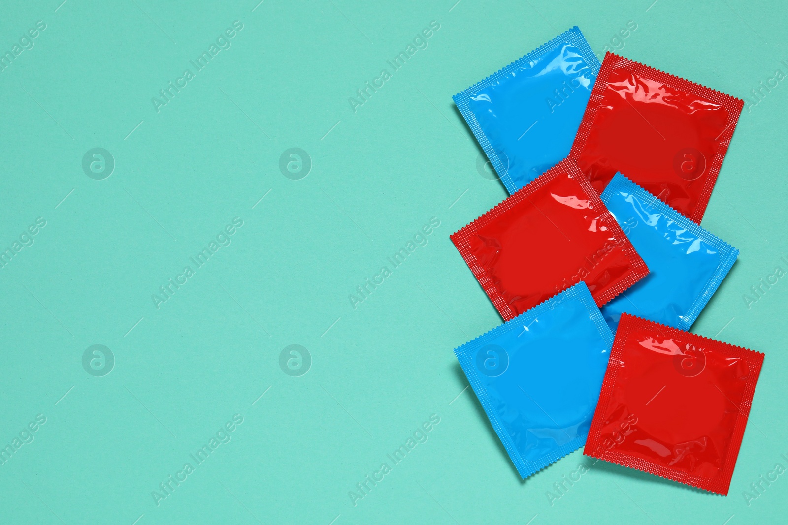 Photo of Condom packages on turquoise background, flat lay and space for text. Safe sex