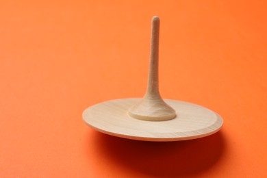 Photo of One wooden spinning top on orange background, space for text