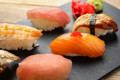 Serving board with delicious nigiri sushi on wooden table, closeup