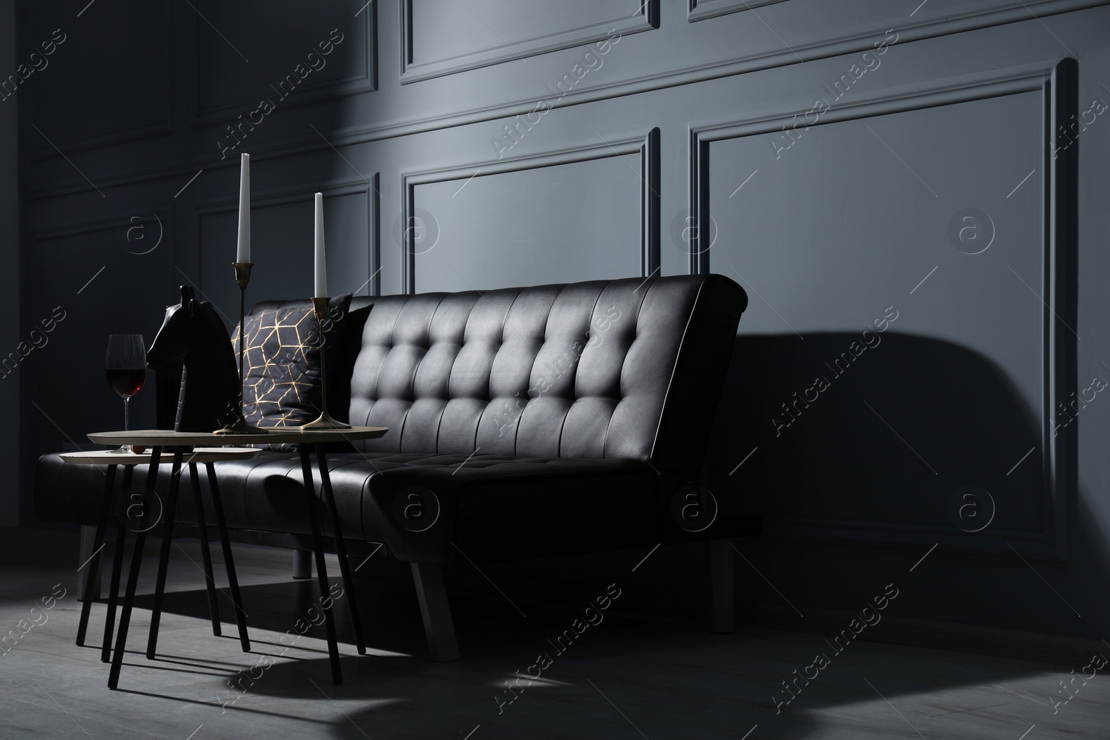 Photo of Elegant leather sofa and candlesticks on coffee table near light grey wall. Interior design