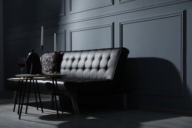 Photo of Elegant leather sofa and candlesticks on coffee table near light grey wall. Interior design