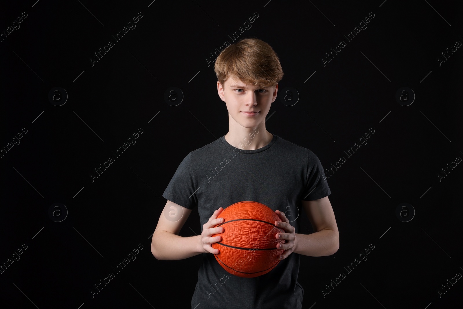 Photo of Teenage boy with basketball ball on black background