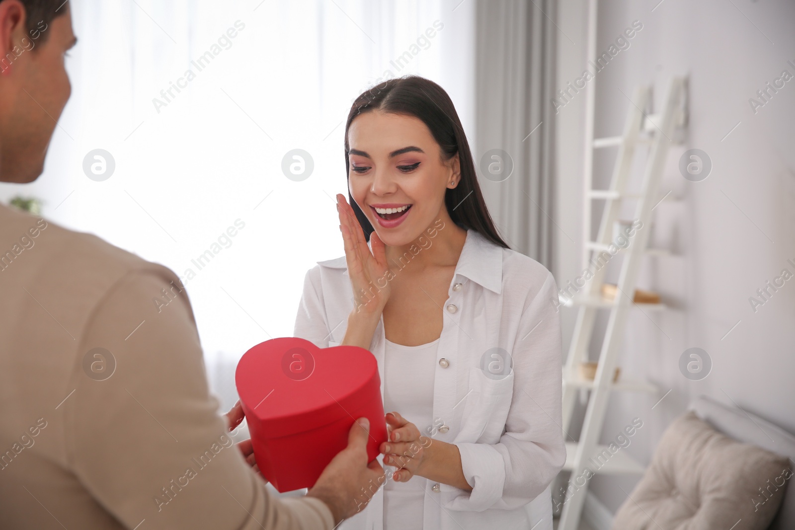 Photo of Man presenting gift to his beloved woman at home. Valentine's day celebration